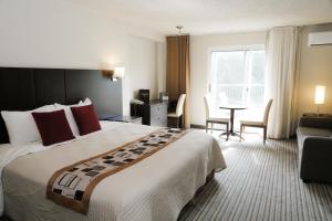 a hotel room with a large bed and a table at Excelsior Hôtel Spa Sainte-Adèle in Sainte-Adèle