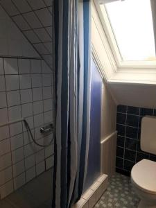 La salle de bains est pourvue d'une douche, de toilettes et d'une fenêtre. dans l'établissement Gästehaus Mia, à Norddeich