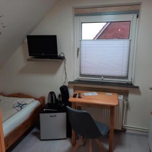 - une chambre avec un bureau, un lit et une fenêtre dans l'établissement Gästehaus Mia, à Norddeich