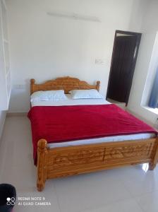 een slaapkamer met een houten bed en een rode deken bij KODAIKANAL HOME STAY in Kodaikānāl