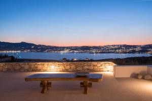 Villa Conza Mykonos في أغيوس يوانيس ميكونوس: مقعد على فناء مطل على الماء