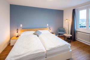 a bedroom with a large white bed with a blue wall at Gasthof zum Schützen in Aarau