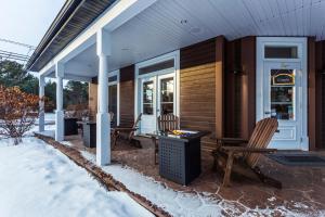 ein Haus mit zwei Stühlen und einem Tisch auf einer Terrasse in der Unterkunft Le 900 Tremblant Inn Café and Bistro in Mont-Tremblant