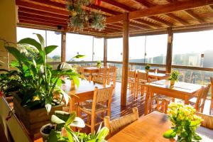 um restaurante com mesas de madeira, cadeiras e plantas em Pousada Morro Verde em Águas de Lindóia