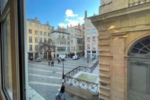 Elle offre une vue sur une rue de la ville depuis sa fenêtre. dans l'établissement Coeur Vieux Lyon, 60 M2 lumineux tout confort, à Lyon