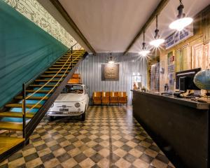 un coche viejo aparcado en una habitación con una escalera en The Yard Hostel, en Catania