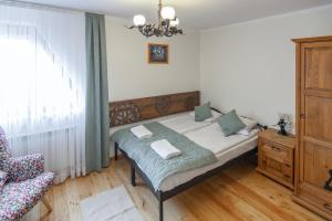 a bedroom with a bed with a chair and a window at Moje Tatry Gluten Free in Biały Dunajec