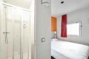 een slaapkamer met een bed en een glazen douche bij Premiere Classe Valence - Bourg Les Valence in Bourg-lès-Valence