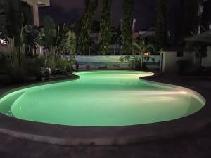 una piscina con illuminazione verde in un giardino di notte di Mudzini gardens - Luxury villa with a pool a Mombasa