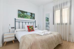 a white bedroom with a bed with towels on it at Holiday Rentals Tempa Museo in Seville