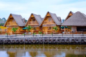 uma fileira de edifícios de madeira com telhados de palha em Pelican Lodge & Marina em Entebbe