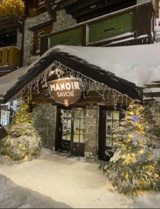 Un cartello di maroon, una cura su un edificio nella neve. di Appartement Manoir de Savoie Arc 1950 a Bourg-Saint-Maurice