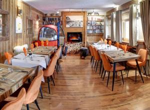 un ristorante con tavoli, sedie e un camino di Hôtel Les Cimes a Megève