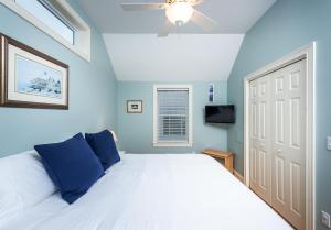 een slaapkamer met een bed met blauwe muren en een plafondventilator bij Owls Head Cottage at One Long Beach in York Beach