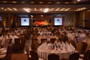 a banquet hall with white tables and chairs and screens at Grand Hotel Napoca in Cluj-Napoca