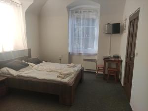 um quarto com uma cama, uma mesa e uma janela em Penzion Klášterský mlýn em RejÅ¡tejn