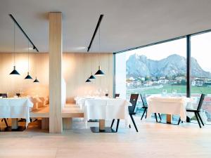 un comedor con mesas blancas y una gran ventana en Schgaguler Hotel, en Castelrotto