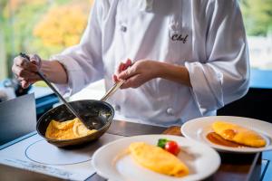 uno chef che prepara il cibo in una padella su un tavolo di ANA Crowne Plaza Matsuyama, an IHG Hotel a Matsuyama