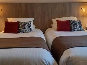 dos camas sentadas una al lado de la otra en una habitación de hotel en Mercure Dinan Port Le Jerzual, en Dinan