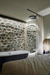 a bathroom with a bath tub and a stone wall at Truma Swing Luxury in Merano