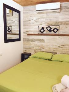 een slaapkamer met een groen bed en een spiegel bij Casa Mamá Waldy New in Cartagena