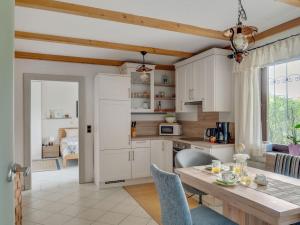 une cuisine avec des placards blancs et une table en bois dans l'établissement Cosy Apartment in Oed hling with Garden, à Mauer bei Amstetten