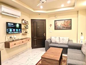 ein Wohnzimmer mit einem Sofa und einem TV in der Unterkunft Tranquil & Delightful 1 Bed Apt In Bahria Town in Rawalpindi