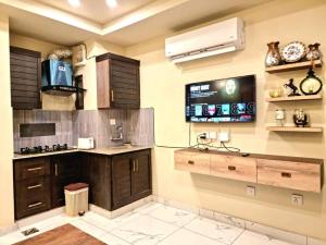 eine Küche mit Holzschränken und einem TV an der Wand in der Unterkunft Tranquil & Delightful 1 Bed Apt In Bahria Town in Rawalpindi