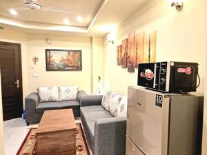 ein Wohnzimmer mit einem Sofa und einem TV auf einem Kühlschrank in der Unterkunft Tranquil & Delightful 1 Bed Apt In Bahria Town in Rawalpindi