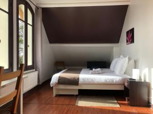 a bedroom with a large bed in a room with windows at LA CHERIELLE in Auvers-sur-Oise