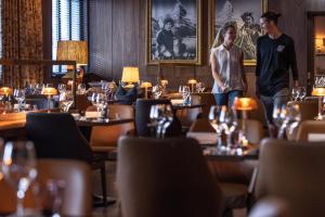 two people standing in a restaurant with tables at Schweizerhof Zermatt - a Small Luxury Hotel in Zermatt