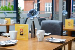 un tavolo di legno con un vaso con un fiore blu di Holiday Inn Bolton Centre, an IHG Hotel a Bolton