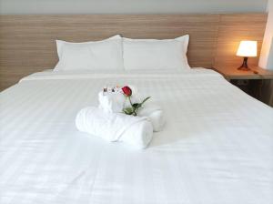 uma cama branca com uma rosa e toalhas em JVAPLACE em Nonthaburi