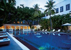 une piscine avec des chaises et un bâtiment dans l'établissement Taj Connemara, Chennai, à Chennai