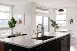 una cucina con pareti bianche, lavandino e finestre di Skyline Loft - Sweeping Views - Central LoHi a Denver