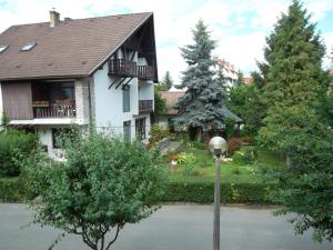 a white house with a balcony and trees at Haus Gizella in Harkány