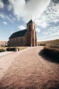 een bakstenen weg die leidt naar een kerk met een klokkentoren bij Strandhotel Zoutelande in Zoutelande