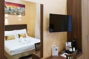 um quarto de hotel com uma cama e uma televisão de ecrã plano em Trinity Luxury Rooms em Roma