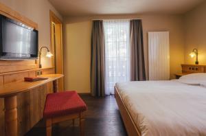 una camera d'albergo con letto, scrivania e TV di Guesthouse by the rex a Zermatt