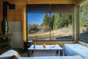 um quarto com uma grande janela com uma mesa em Wood Cabin by the River - for Nature Lovers em Vytina