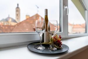 two wine glasses and a bottle on a window sill at Hotel U Vlašského Dvora in Kutná Hora