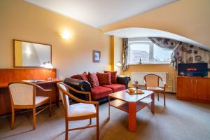 a living room with a red couch and chairs at Hotel U Vlašského Dvora in Kutná Hora