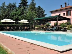 een zwembad met stoelen en parasols naast een huis bij Agriturismo La Prosciutta in Faenza