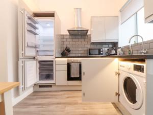 a kitchen with white cabinets and a washer and dryer at Battell Chambers in Camborne