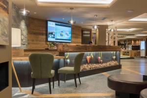 a lobby with a bar with two chairs and a fish tank at Hotel Lac Salin Spa & Mountain Resort in Livigno