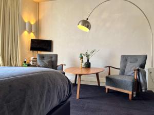 um quarto com uma cama, 2 cadeiras e uma mesa em Van der Gang Suites em Dokkum