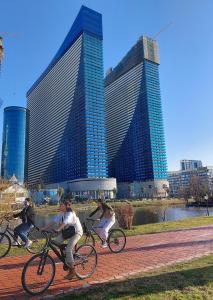 un groupe de personnes faisant du vélo devant de grands bâtiments dans l'établissement Twins tower orbi city, à Batoumi