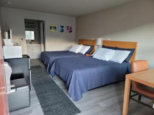 a bedroom with two beds with blue sheets and a table at Garden of the Gods Motel in Colorado Springs