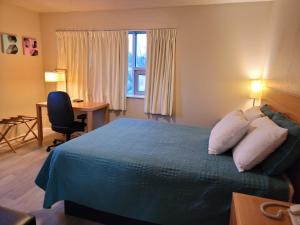 a hotel room with a bed and a desk and a window at Garden of the Gods Motel in Colorado Springs