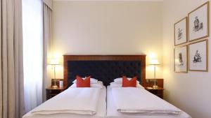 a hotel room with two beds with red pillows at Hotel Kaiserhof Wien in Vienna